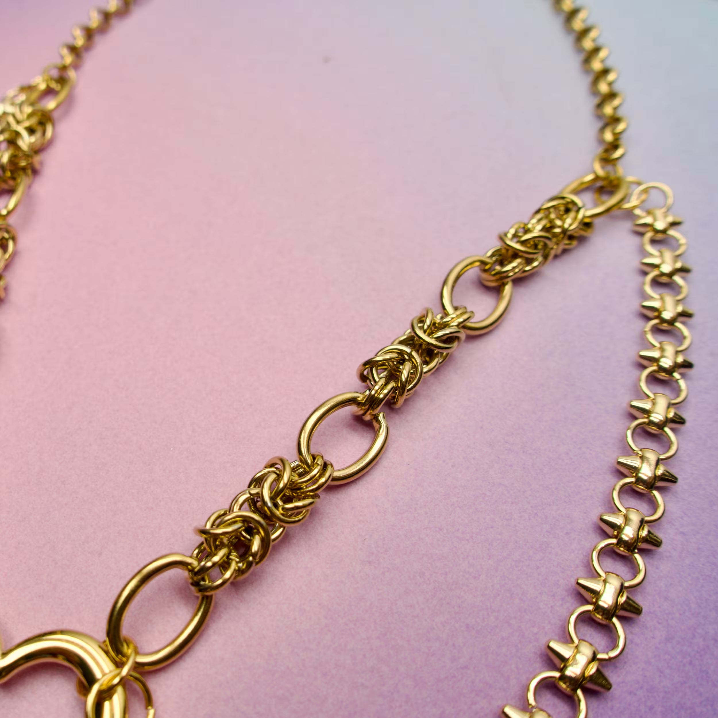 Gold punk chain necklace on a pink background