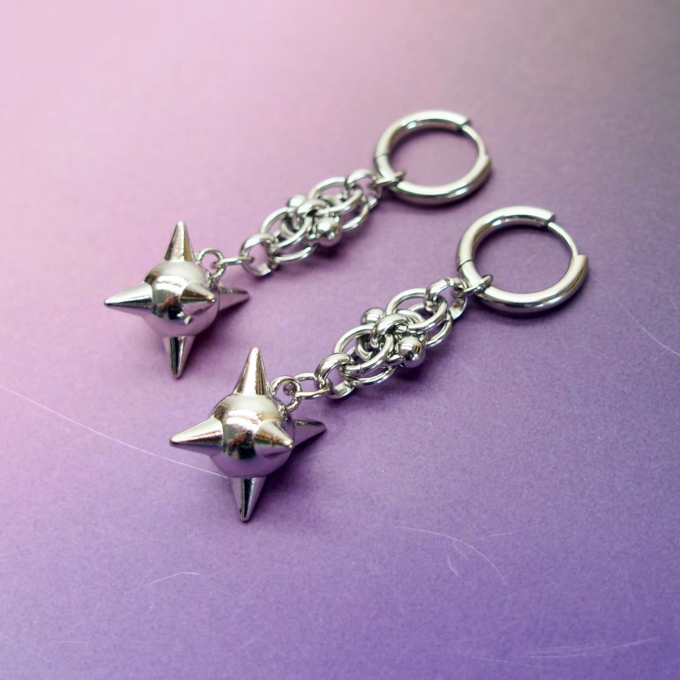 Medieval mace-inspired silver earrings — spiked orbs on stainless steel chain for alternative style lovers.