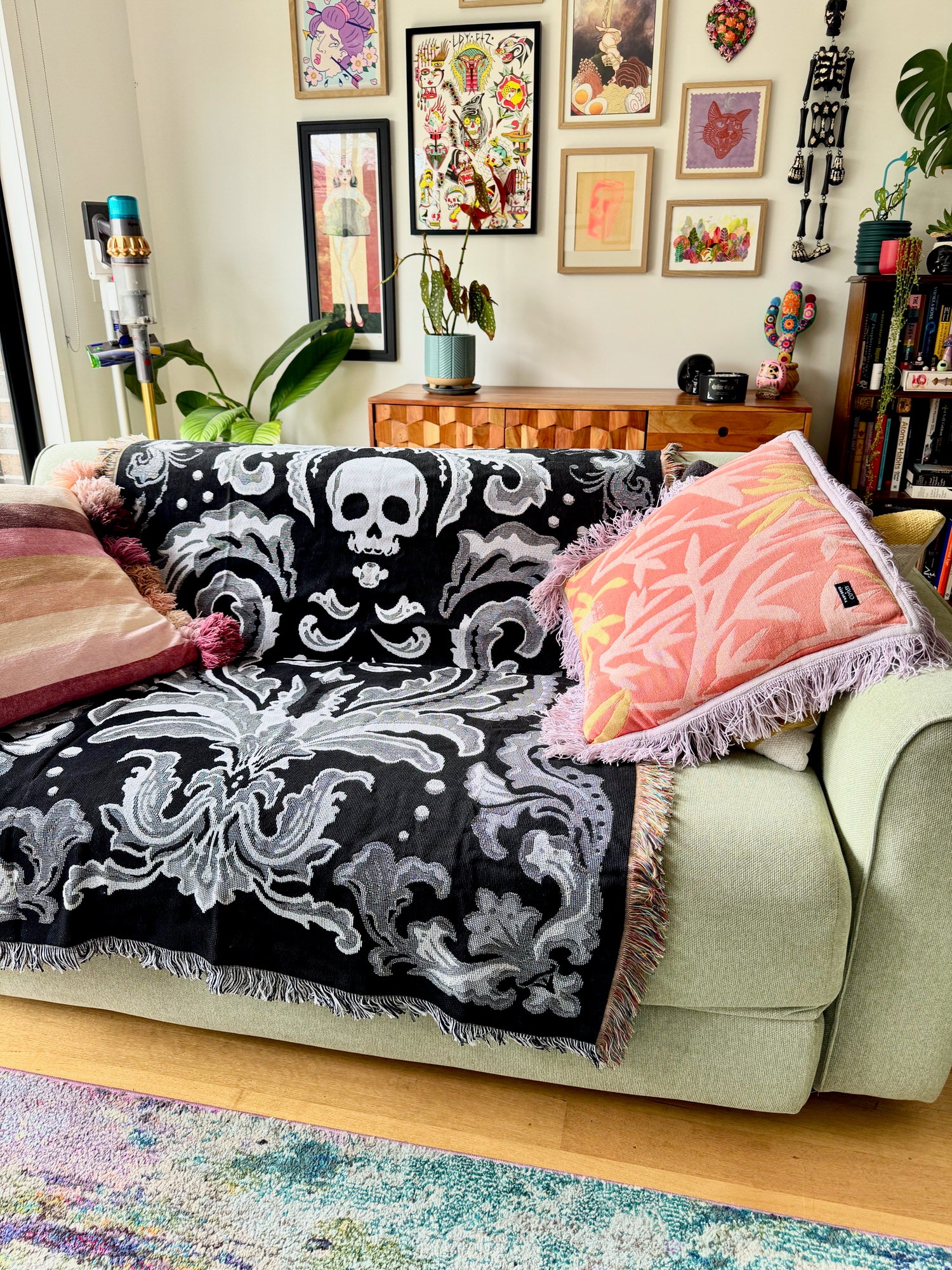 Decorative black and white patterned throw blanket on a light green sofa with colorful pillows in a living room.