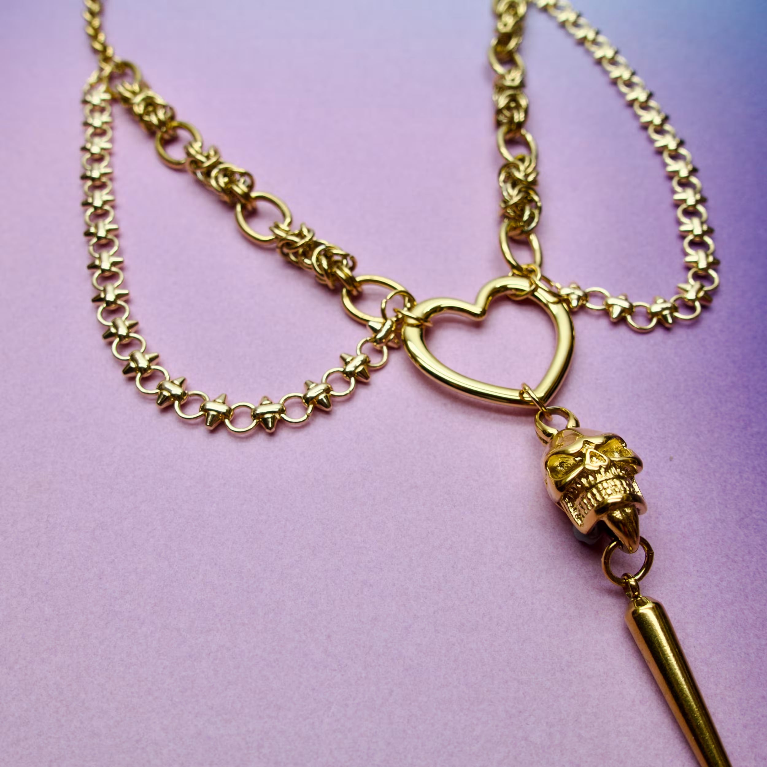 Close-up of gold chain punk jewellery featuring a skull and spike pendant detail.
