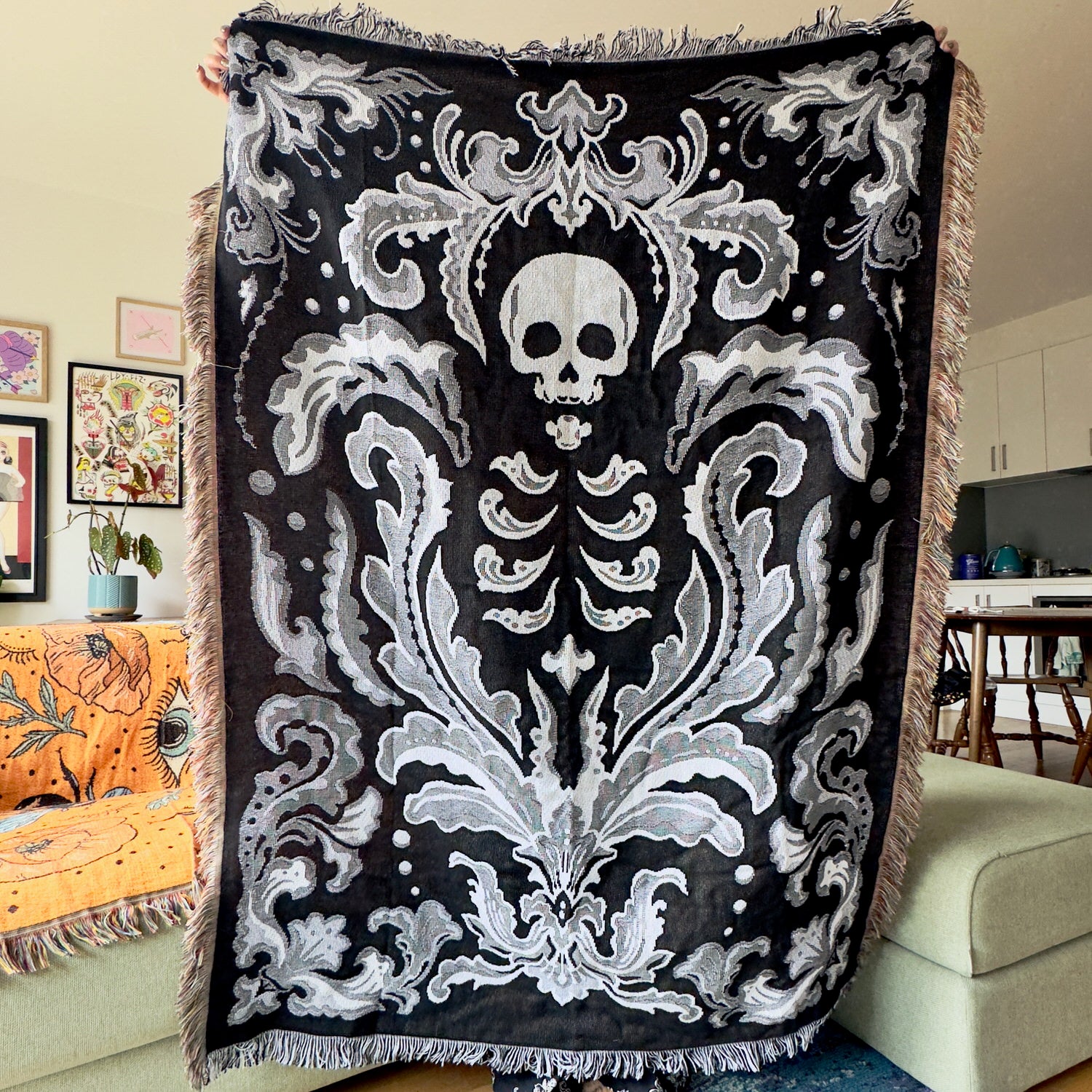 Decorative throw blanket with skull and skeleton design in a living room setting