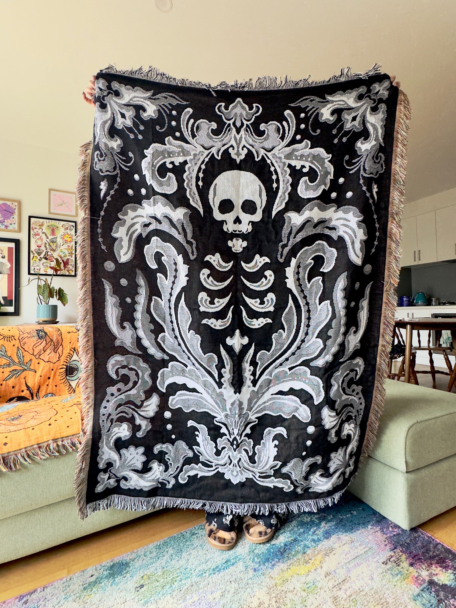 Decorative throw blanket with skeleton design draped over a couch in a living room.